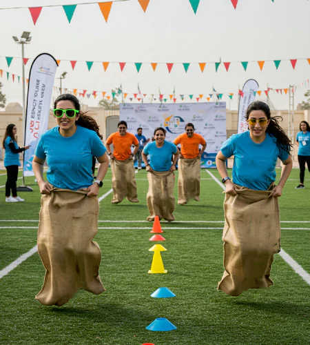 Outrageous Team Adventure team-building activity in Dubai featuring employees competing in a sack race, promoting teamwork, agility, and friendly competition