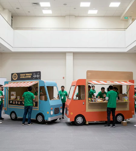Food truck team-building challenge with teams constructing and decorating mini food stalls during an indoor event hosted by MRM Events.
