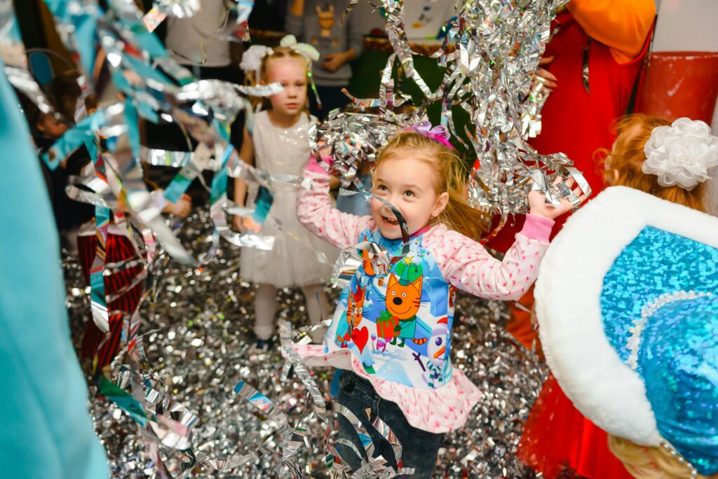 Children playing joyfully with metallic streamers at a colourful family event organised by MRM Events.