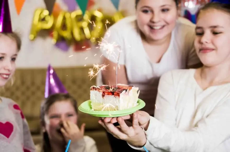 Girls smiling at a cake with a sparkler at a celebration organised by MRM Events in Dubai.