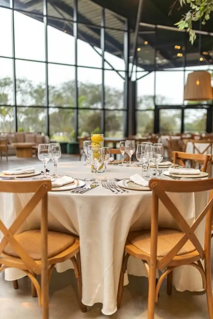 Elegant round table set with glassware and wooden chairs in a bright venue, highlighting MRM Events' upscale event setups.