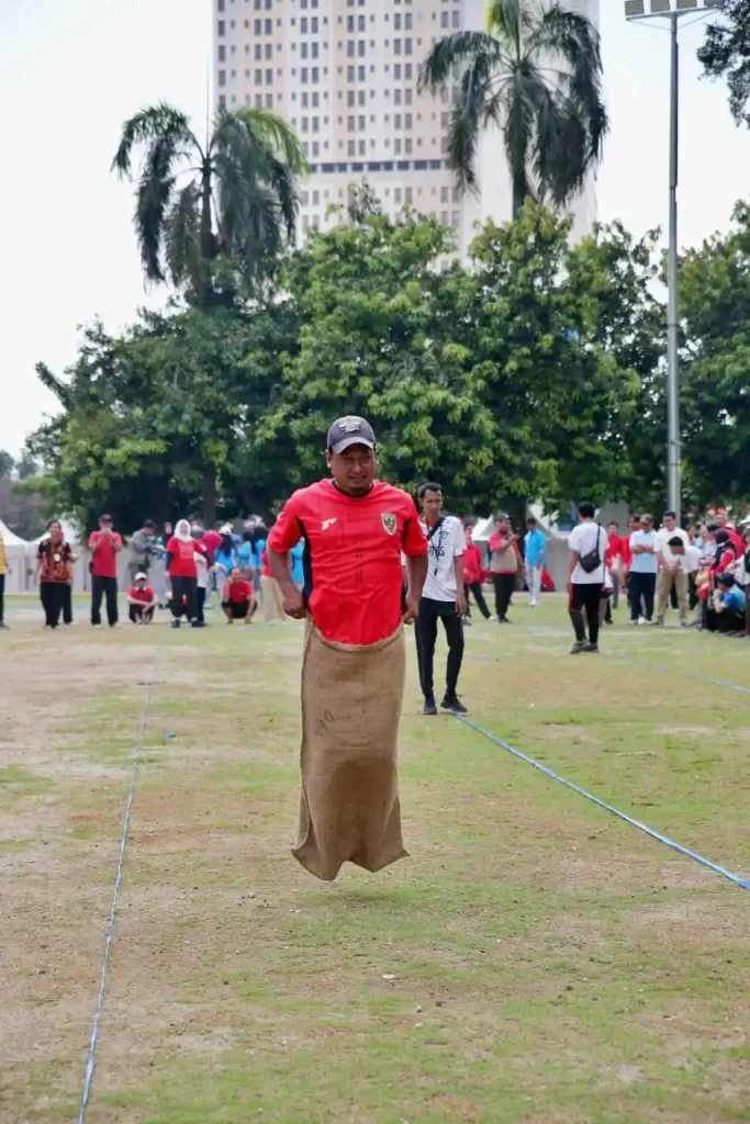 Participant racing in a sack race during an outdoor team-building event by MRM Events.