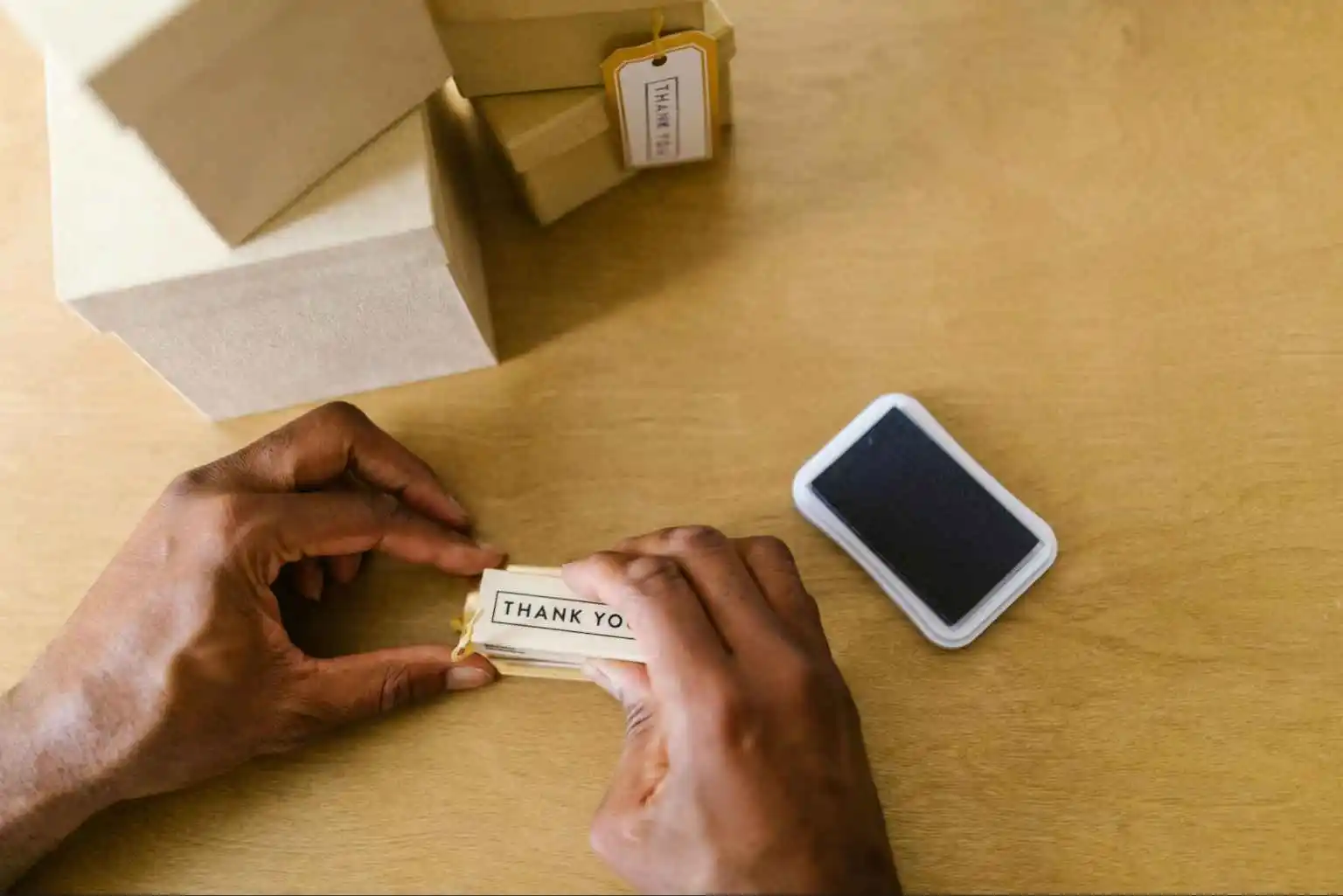 Close-up of hands applying 'Thank You' labels to packages for event guests at an MRM Events function.