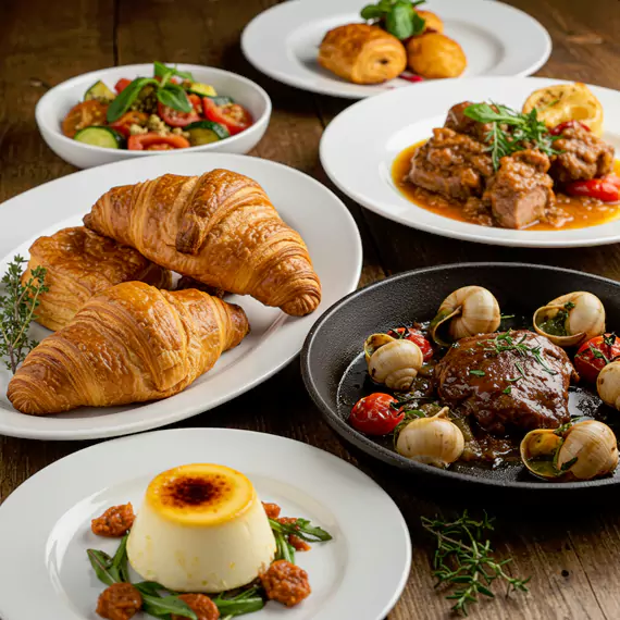 A refined business meeting catering setup, featuring gourmet dishes like croissants, lamb stew, and creamy panna cotta, perfect for corporate catering services in Dubai.