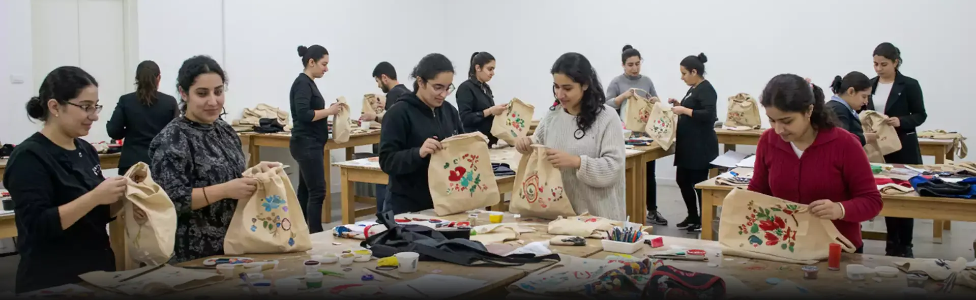 Corporate professionals designing hand-painted tote bags in a craft workshop in Dubai, exploring creativity through custom artwork on fabric