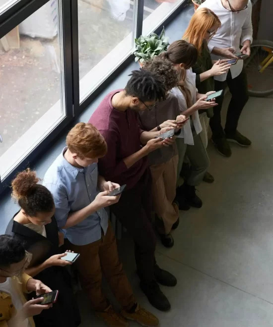 Group of people chatting and using smartphones near floor-to-ceiling windows at a product launch event organised by MRM Events.